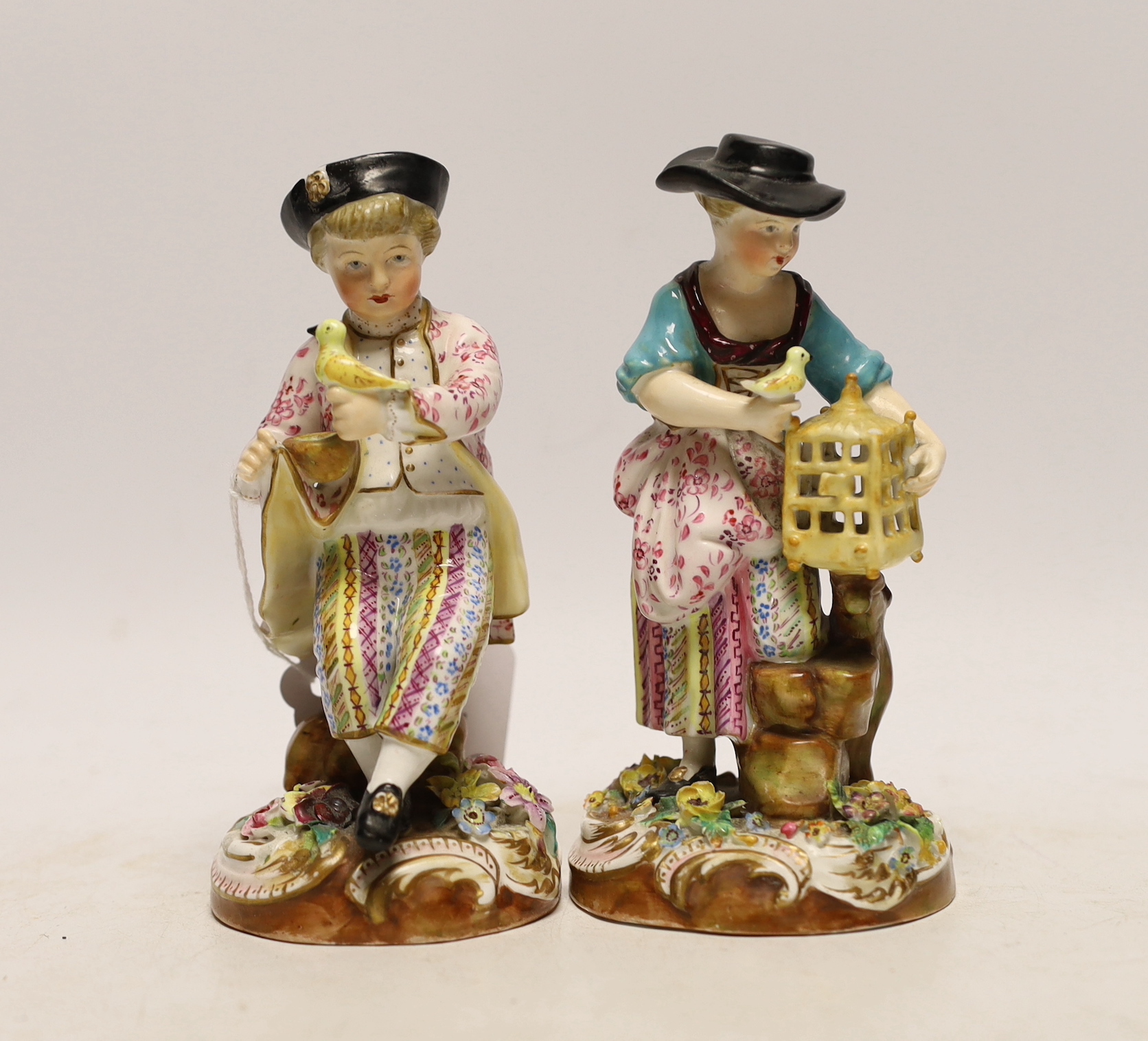 A pair of John Bevington figures, late 19th century, both holding birds with floral encrusted bases, 15.5cm